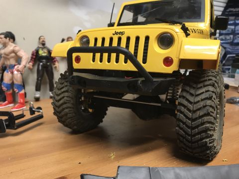 1989 Ford Bronco - A yellow toy Jeep Wrangler is shown from the front, with large off-road tires and a black bull bar.