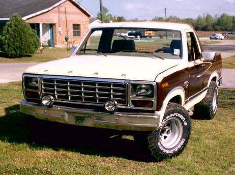 1980 Ford Bronco - A two-tone 1980 Ford Bronco is parked on a grassy lawn in front of a house.
