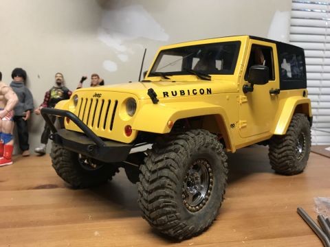 1989 Ford Bronco - A remote-controlled Jeep Wrangler sits on a wooden surface, with action figures in the background.