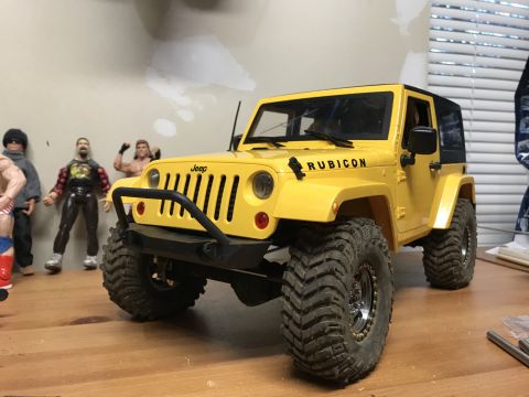 1989 Ford Bronco - A yellow toy Jeep Wrangler with off-road tires is displayed on a table.
