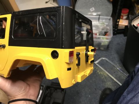 1989 Ford Bronco - The rear section of a yellow Jeep Wrangler body is held by a hand, with a black hardtop and spare tire mount visible.
