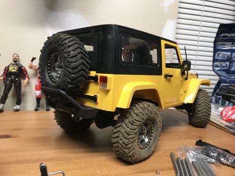 1989 Ford Bronco - A yellow toy Jeep with a black hardtop and a spare tire mounted on the rear bumper is displayed on a wooden surface.