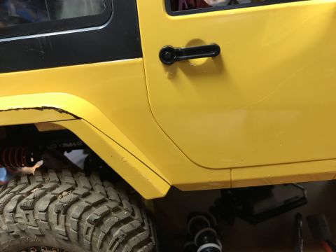 1989 Ford Bronco - Close-up of a yellow Jeep's side door and fender, showing the tire and suspension components.