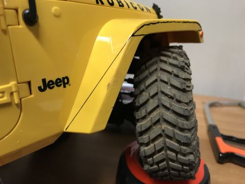 1989 Ford Bronco - Close-up of a yellow Jeep Rubicon fender and off-road tire, with visible black trim and a "Jeep" logo.