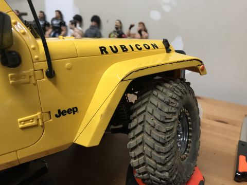 1989 Ford Bronco - Close-up of a yellow Jeep Rubicon model, showing its off-road tires and branding.