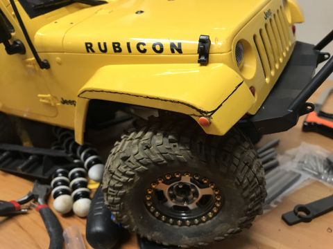1989 Ford Bronco - A close-up view of a yellow Jeep Wrangler Rubicon model, showing its distinctive grille and tire details.
