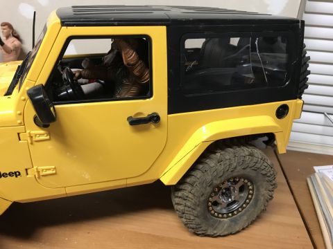 1989 Ford Bronco - A yellow toy Jeep Wrangler is shown from the side, a figure in the driver's seat.