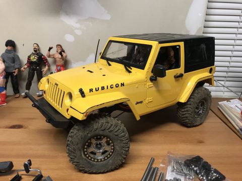 1989 Ford Bronco - RC Jeep Wrangler Rubicon model with action figures in the background.