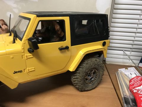 1989 Ford Bronco - A yellow toy Jeep Wrangler sits on a wooden surface, with a figure in the driver's seat.