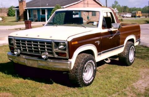 1980 Ford Bronco - This 1980 Ford Bronco is shown from a three-quarter front angle, highlighting its two-tone paint scheme and off-road tires.
