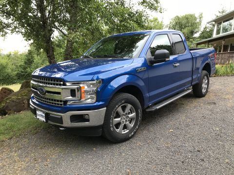 2018 Ford F-150 - A blue 2018 Ford F-150 truck is parked outdoors near a house and trees.