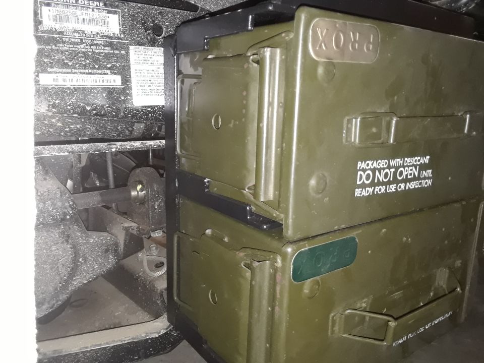 Close-up of green storage boxes labeled 'PROX' stacked on John Deere equipment