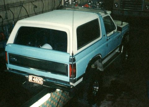 1996 Ford Bronco - This light blue and white Ford Bronco is viewed from the rear, showing its two-tone paint and roof rack.