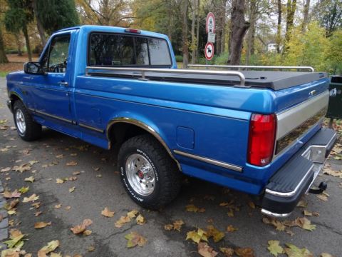 1994 Ford F-150 - A blue 1994 Ford F-150 pickup truck is seen from a three-quarter front view on an autumn day.