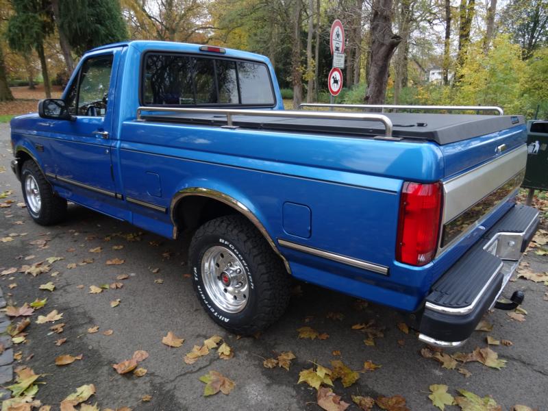 Blue 1994 Ford F-150 pickup truck parked on a street with fallen leaves