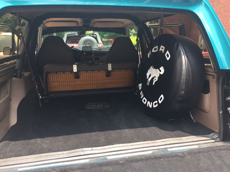 Teal 1996 Ford Bronco interior cargo area with spare tire cover, wicker basket, and seats