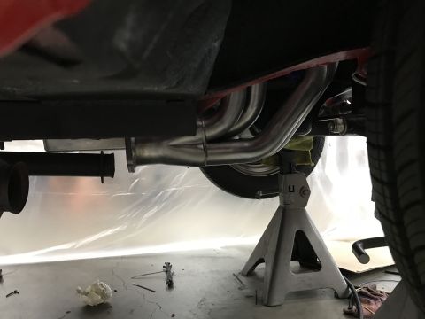 1964 Ford Fairlane - The exhaust system of a vehicle is visible from underneath, supported by jack stands.