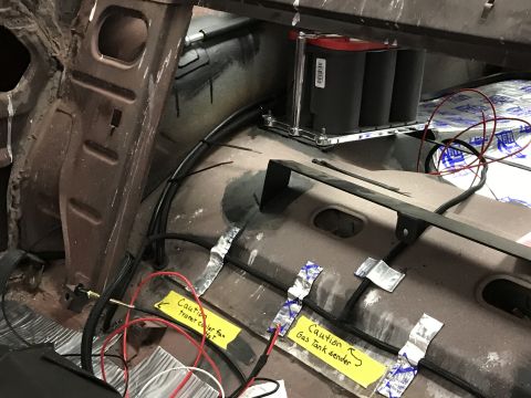 1964 Ford Fairlane - The interior of a car shows a newly installed battery pack and extensive wiring, with caution labels for the transmission cooler fan and ga…