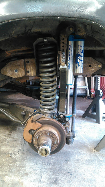 1978 Ford Bronco - Close-up of a vehicle's front suspension system, aftermarket Fox Racing shocks and a heavy-duty coil spring.