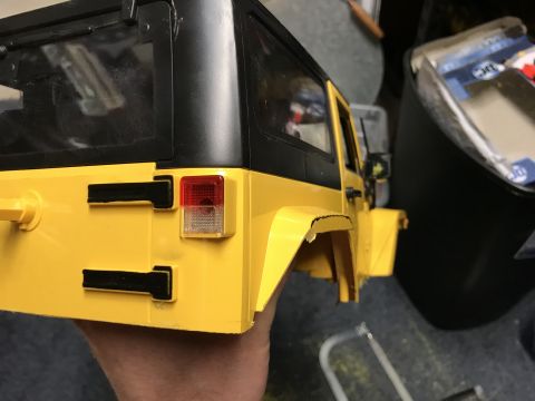 1989 Ford Bronco - A yellow RC Jeep Wrangler body is held up, showing its rear details and black hardtop.