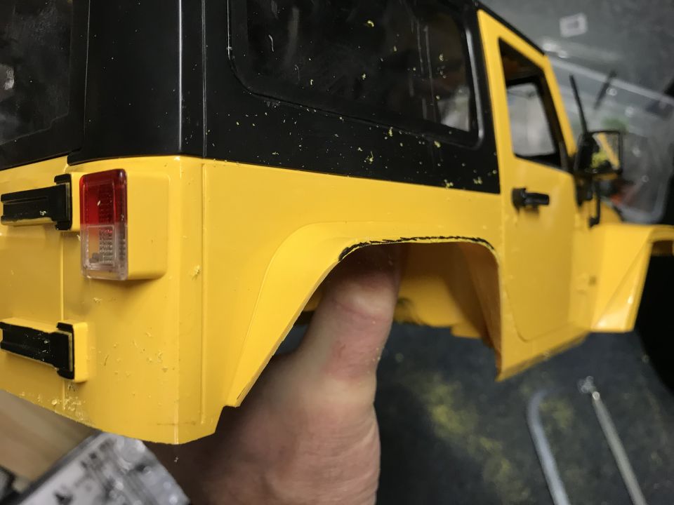 Yellow toy jeep body, black hardtop, rear taillight visible, held by a hand