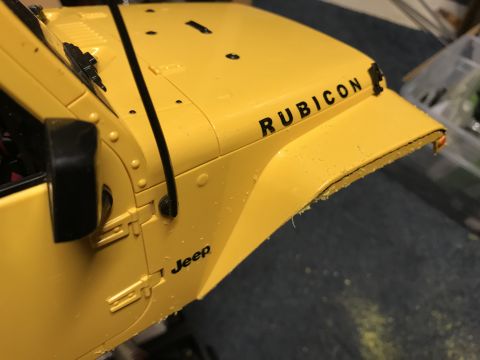 1989 Ford Bronco - Close-up of a yellow Jeep Rubicon fender and hood section, showing the 'Jeep' and 'Rubicon' badging.