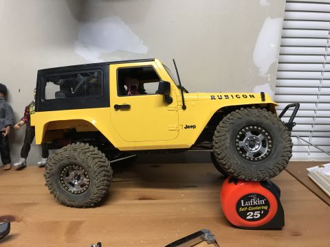 1989 Ford Bronco - A yellow toy Jeep Wrangler Rubicon is shown from the side, resting on a tape measure.