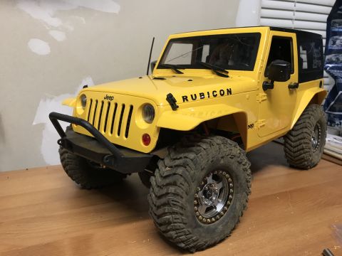 1989 Ford Bronco - This yellow Jeep Wrangler Rubicon features prominent "Rubicon" badging on the hood and large, aggressive off-road tires.