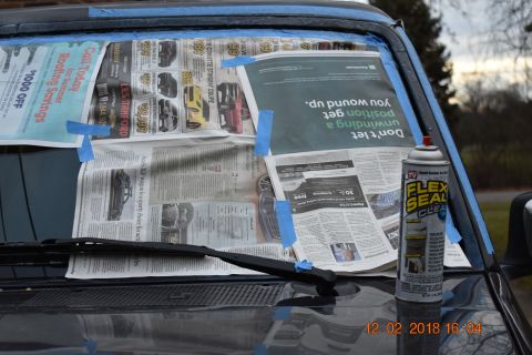 1996 Ford Bronco - A vehicle's windshield is covered with newspaper and tape, with a can of sealant ready for use.