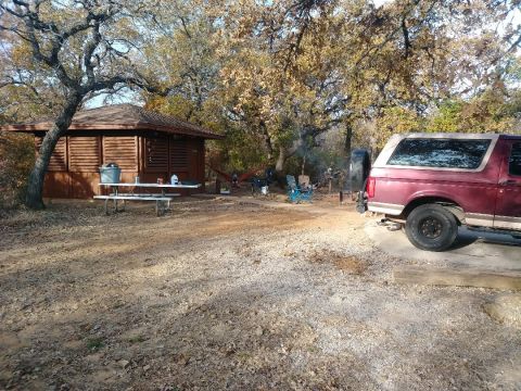 1996 Ford Bronco - A red Ford Bronco is parked at a campsite next to a cabin, with a campfire burning.