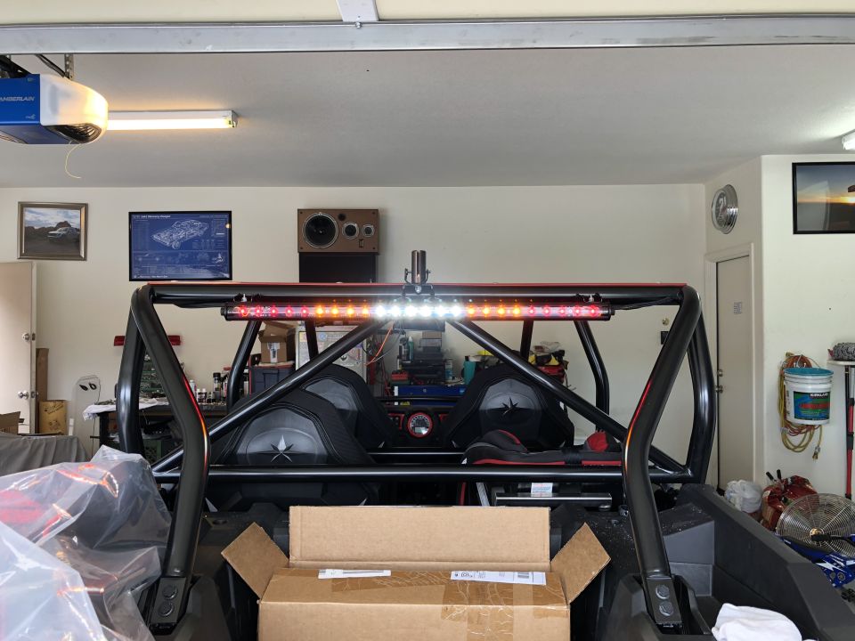 Rear view of a roll cage with a light bar and two seats inside a garage
