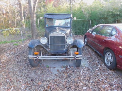 1909 Ford Model T - A vintage car with a distinctive grille is parked outdoors next to a modern sedan.
