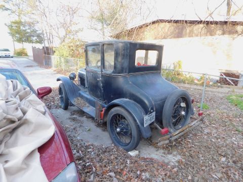 1909 Ford Model T - A vintage black coupe sits in a driveway covered in fallen leaves, with a spare tire mounted on the rear.