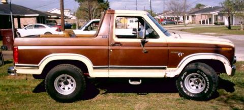 1980 Ford Bronco - Side profile of a two-tone brown and cream Ford Bronco parked on grass.