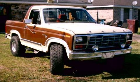 1980 Ford Bronco - This two-tone Ford Bronco is parked on a grassy lawn in front of a residential building.