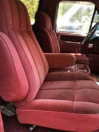 1986 Ford Bronco - Interior view of red velour bucket seats and armrest in a 1986 Ford Bronco.