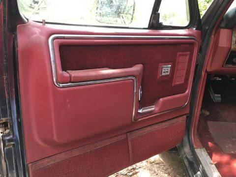 1986 Ford Bronco - Interior view of a vehicle's red door panel, showing the armrest and window controls.