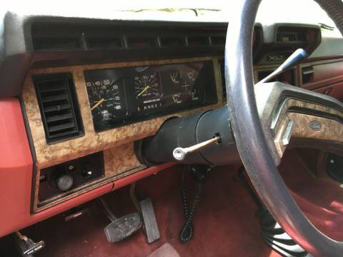 1986 Ford Bronco - The dashboard interior shows a wood grain trim and red upholstery, indicative of a 1980s Ford truck.