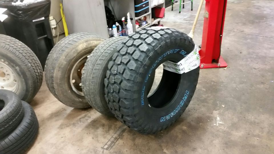 New Ironman All Country M/T mud tire standing in a shop next to old worn tires
