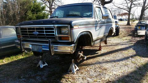 1986 Ford Bronco - This 1980s Ford Bronco is elevated on jack stands, with its wheels removed, suggesting it is undergoing repairs.