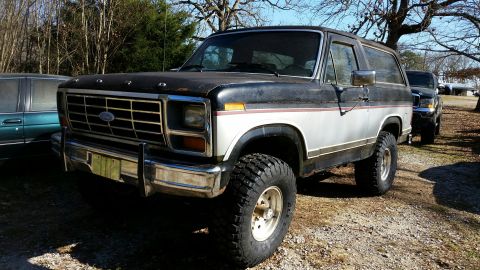 1986 Ford Bronco - This 1986 Ford Bronco is parked outside with another vehicle behind it.