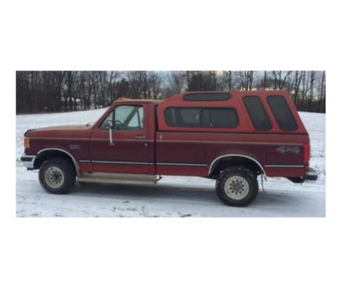 1991 Ford F-150 - A red 1991 Ford F-150 pickup truck is parked in a snowy outdoor setting, viewed from its side.