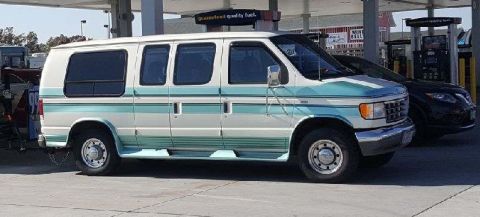1971 Ford Ranchero - A two-tone van is parked at a gas station, with another vehicle visible behind it.