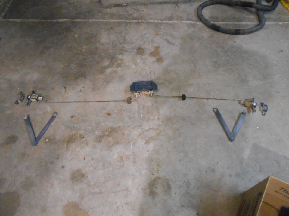 Door lock actuator linkage assembly laid out on concrete floor