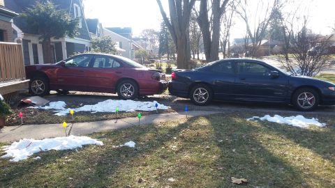 Red and dark blue Pontiac Grand Prix sedans parked next to each other with snow on the ground.