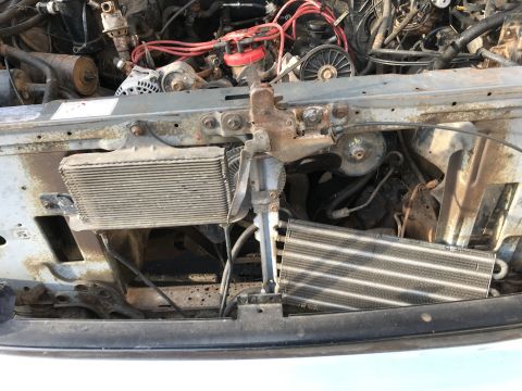 1992 Ford Bronco - Close-up view of the front engine bay of a 1992 Ford Bronco, showing the radiator and transmission cooler. The engine components appear age…