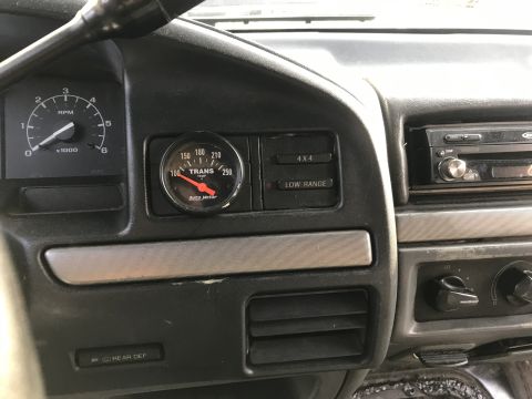 1992 Ford Bronco - The interior of a 1992 Ford Bronco shows a dashboard with a tachometer, a transmission temperature gauge, and a radio.