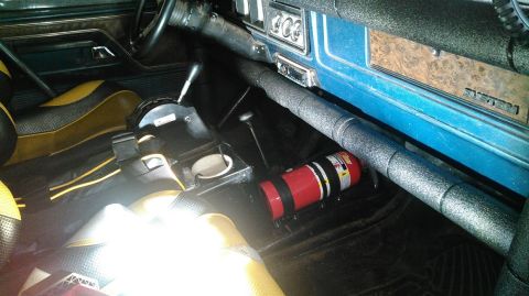 1978 Ford Bronco - The interior of a modified vehicle shows a racing seat with yellow and black upholstery, a floor-mounted shifter, and a red fire extinguish…