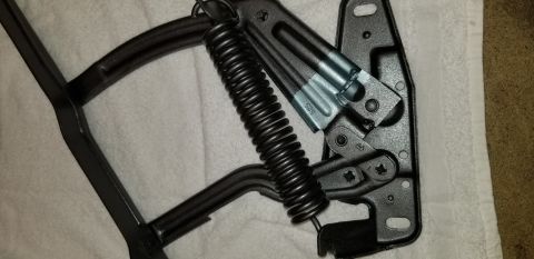 1970 Chevrolet Camaro - A black hood hinge assembly with a coiled spring is shown laid out on a white towel. The hinge has some stamped markings, including '525' a…
