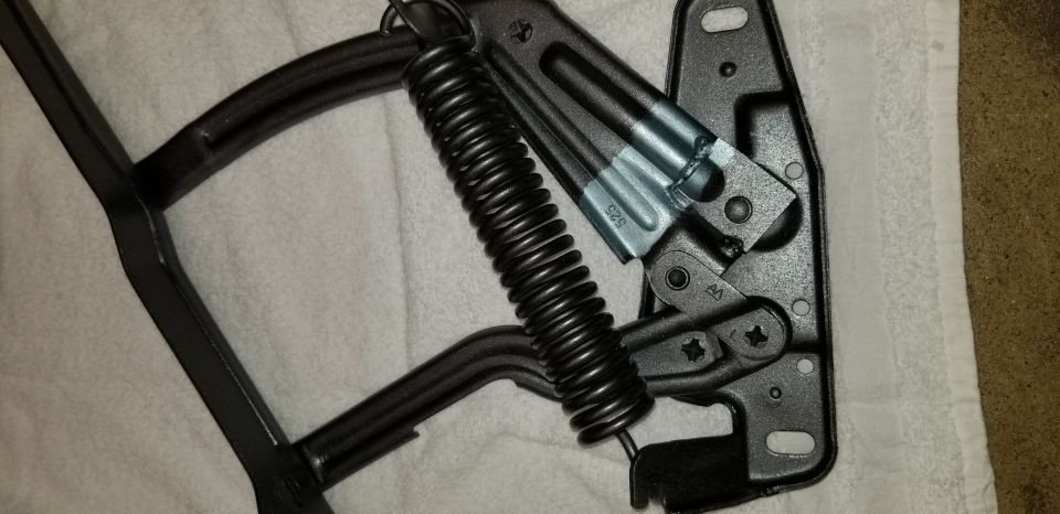 Black hood hinge assembly with coiled spring and stamped markings.